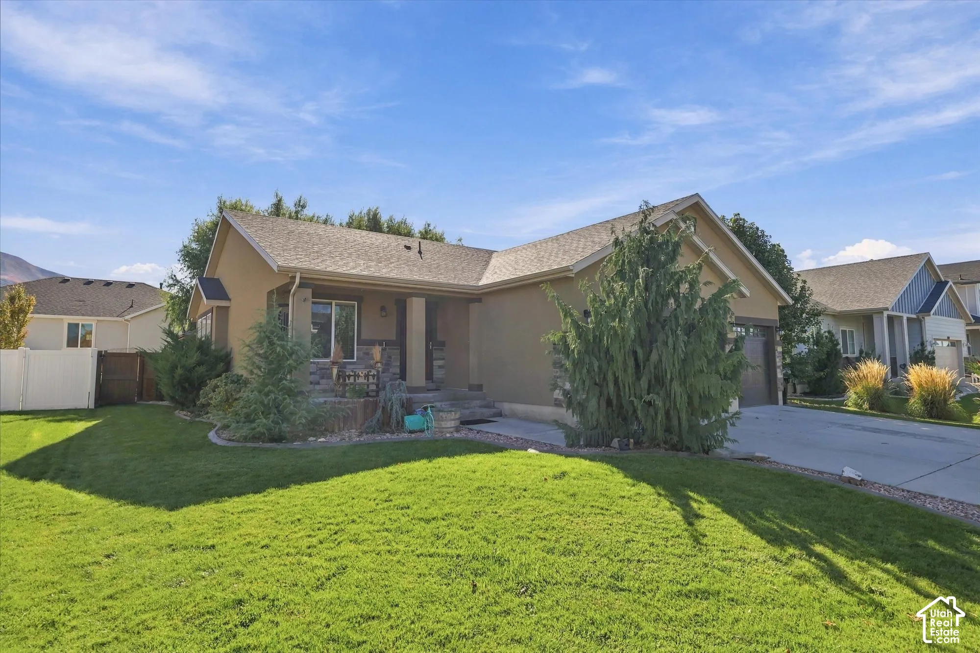 Stucco exterior featuring stacked stone masonry accents, a covered front entryway, an attached garage, and a concrete driveway