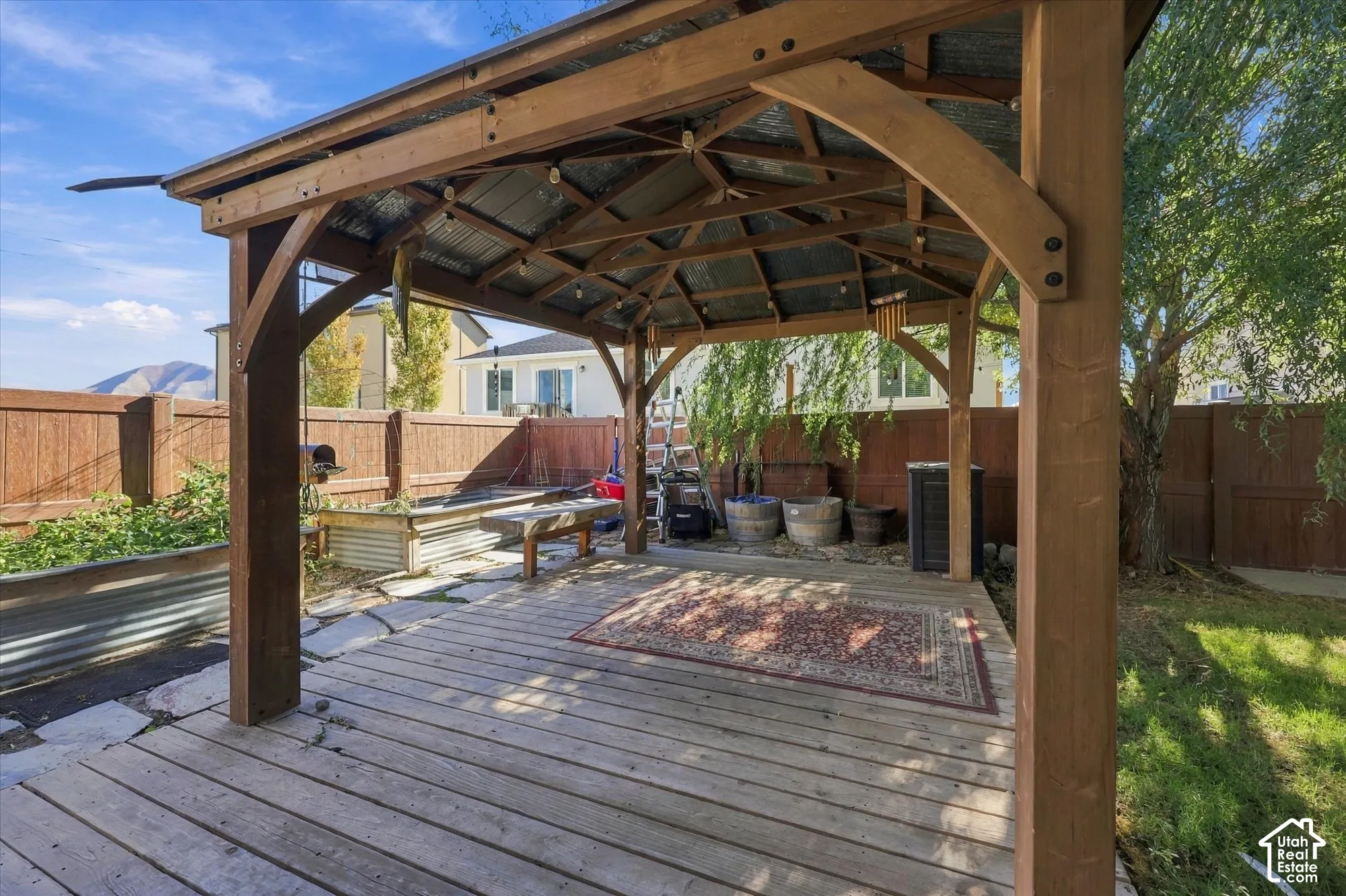 Custom timber-framed gazebo featuring a corrugated metal roof, wood decking, and integrated string lighting