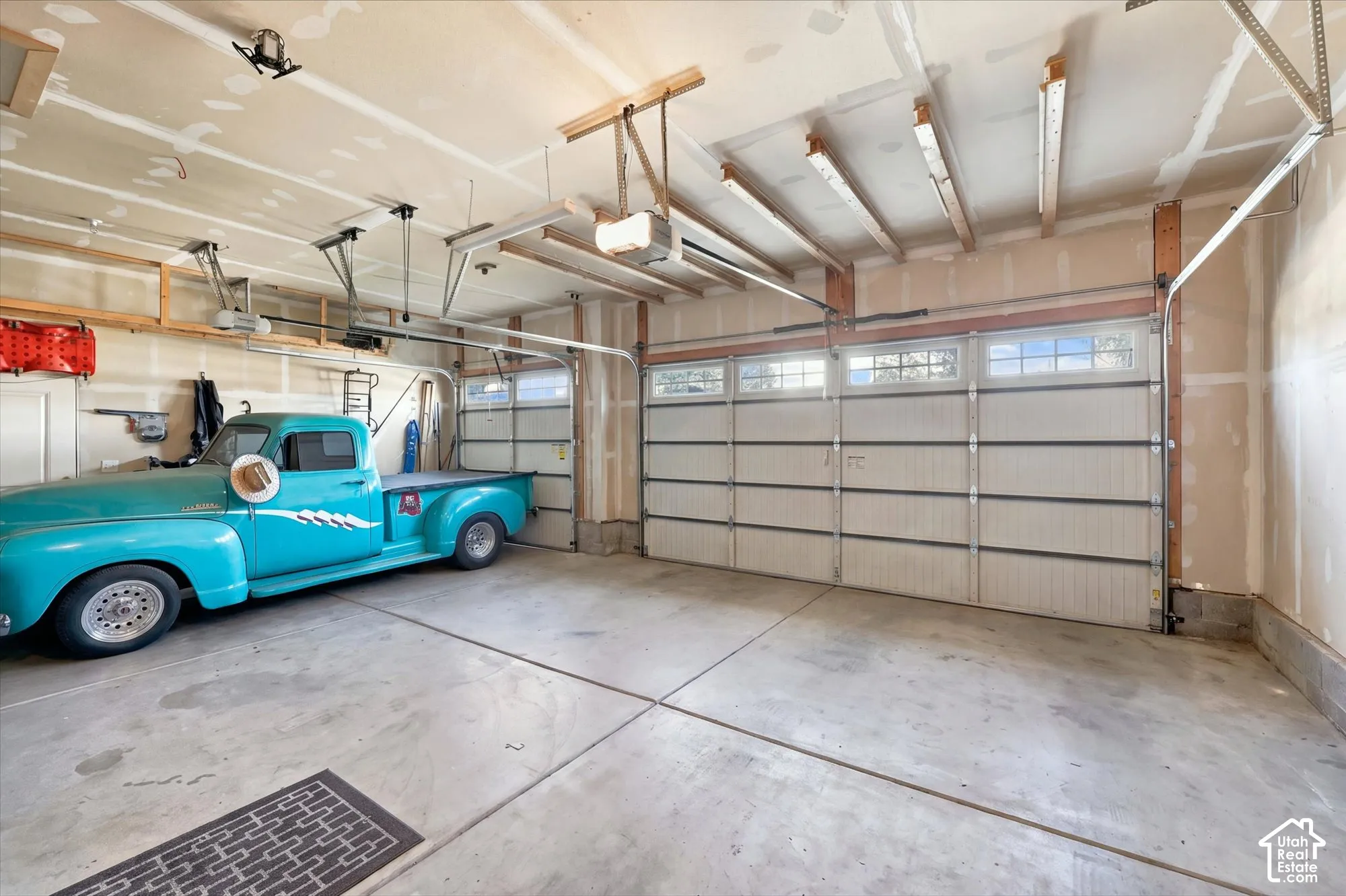 Three-car garage featuring a concrete floor, exposed structural beams, ceiling-mounted automatic garage door openers, and multi-panel doors with inset windows
