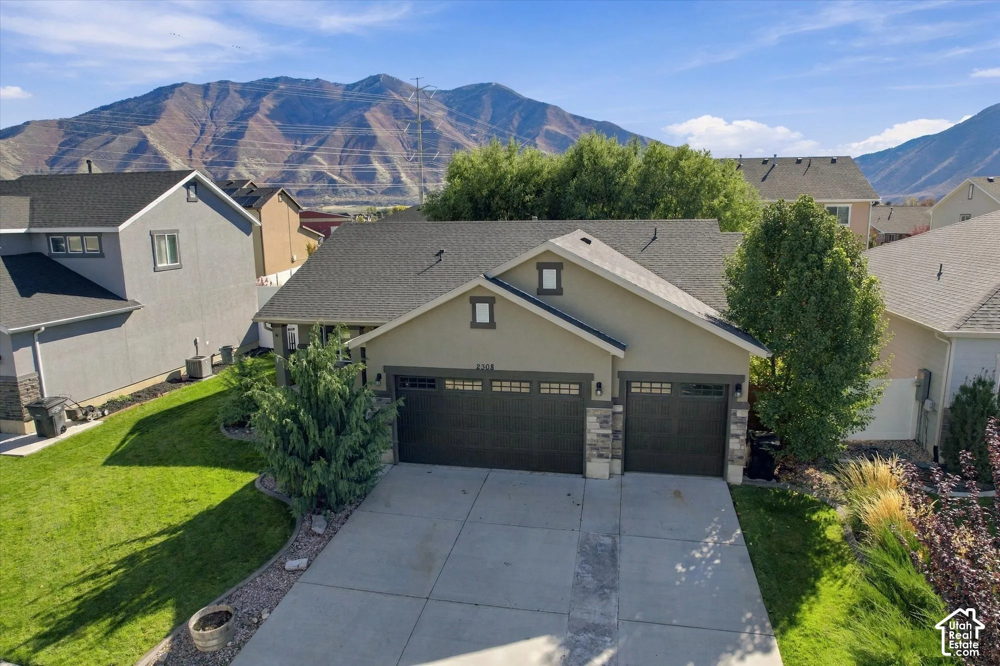 Exterior featuring a three-car garage, stone veneer accents, multi-pane garage windows, and mountain scenery