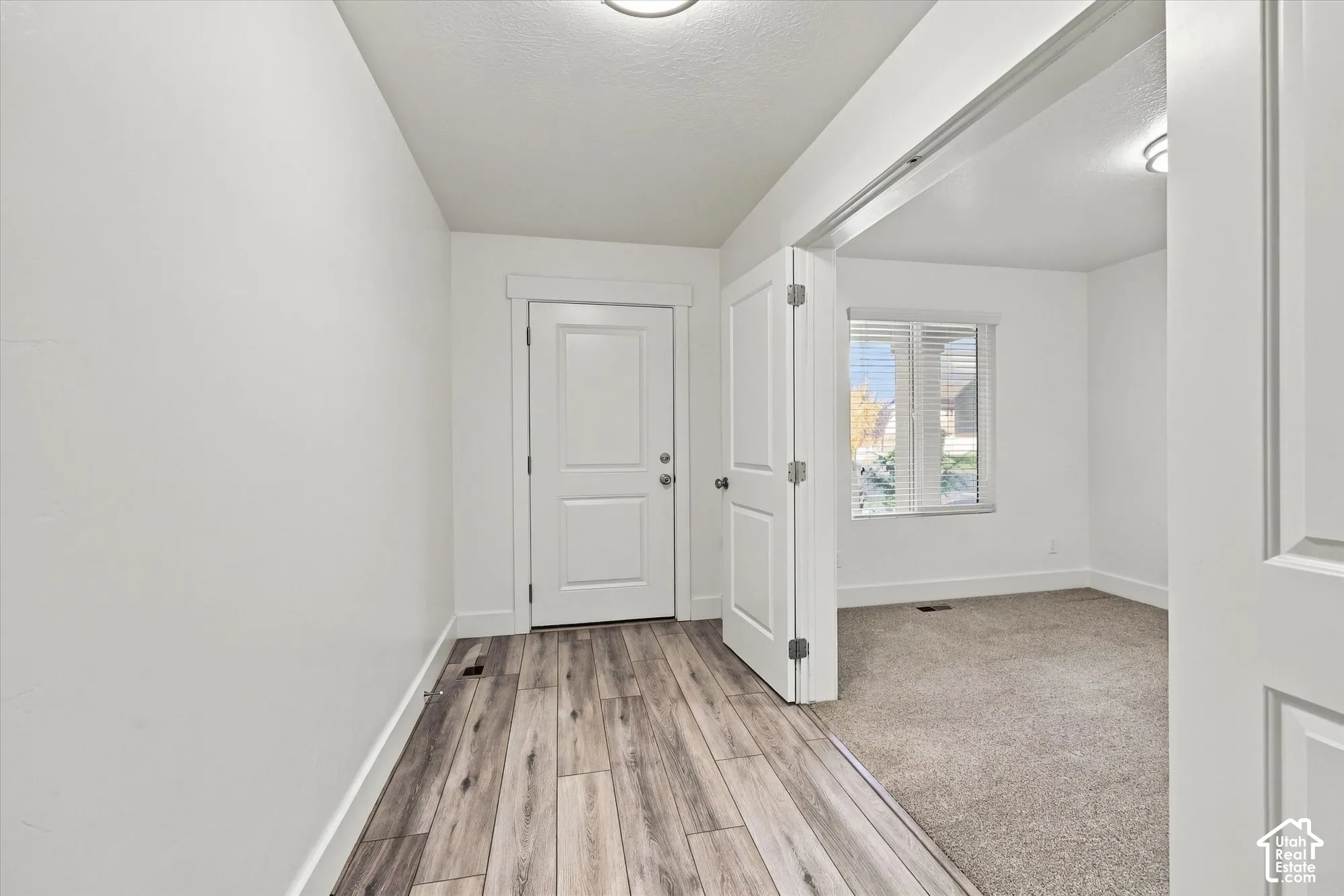Entryway featuring wood-finish flooring, a multi-panel door, and a wide interior doorway with double-hinged doors