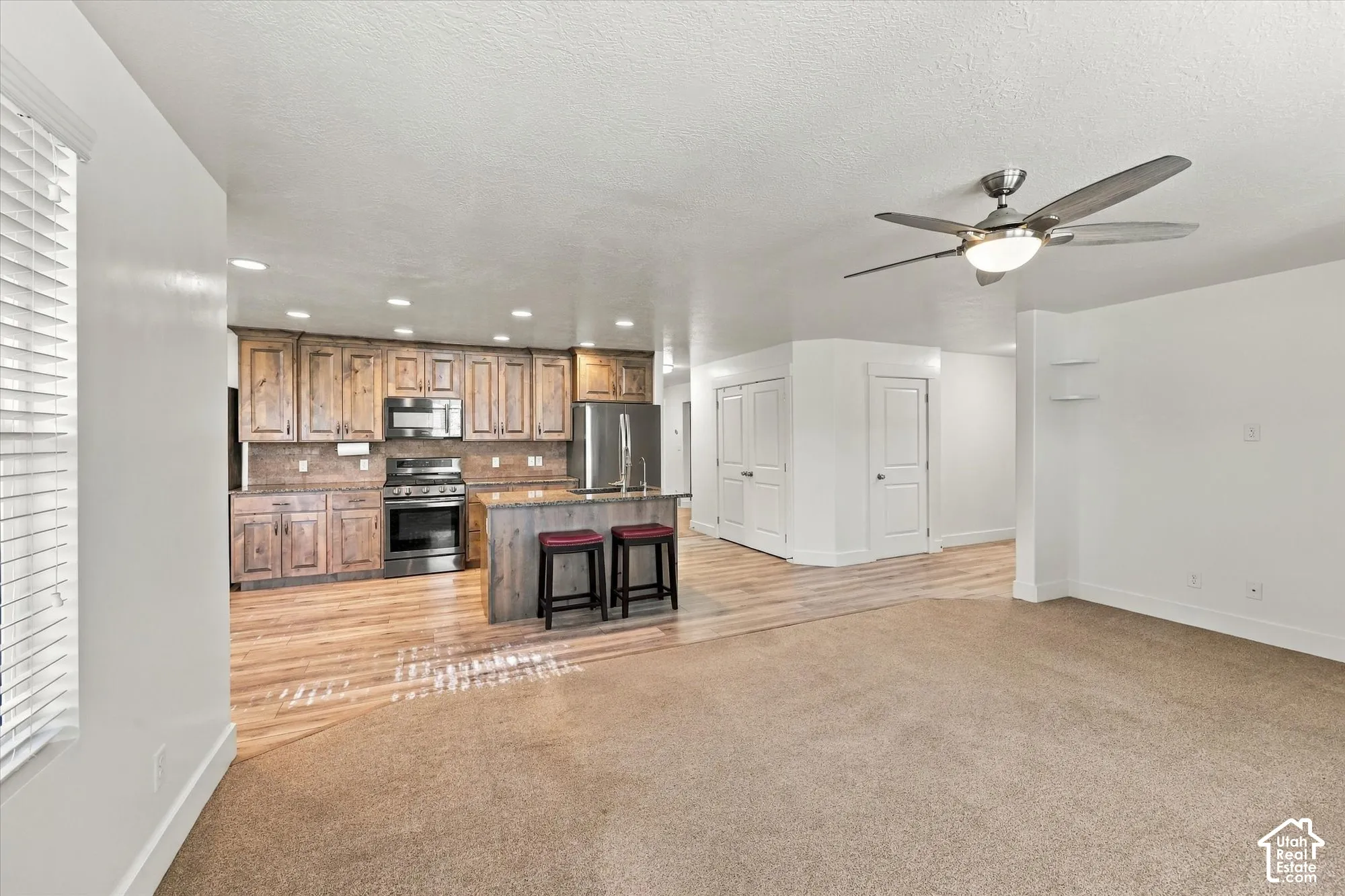 Kitchen featuring stained-wood cabinetry, stone-finish countertops, stainless steel appliances, a kitchen island, and recessed lighting