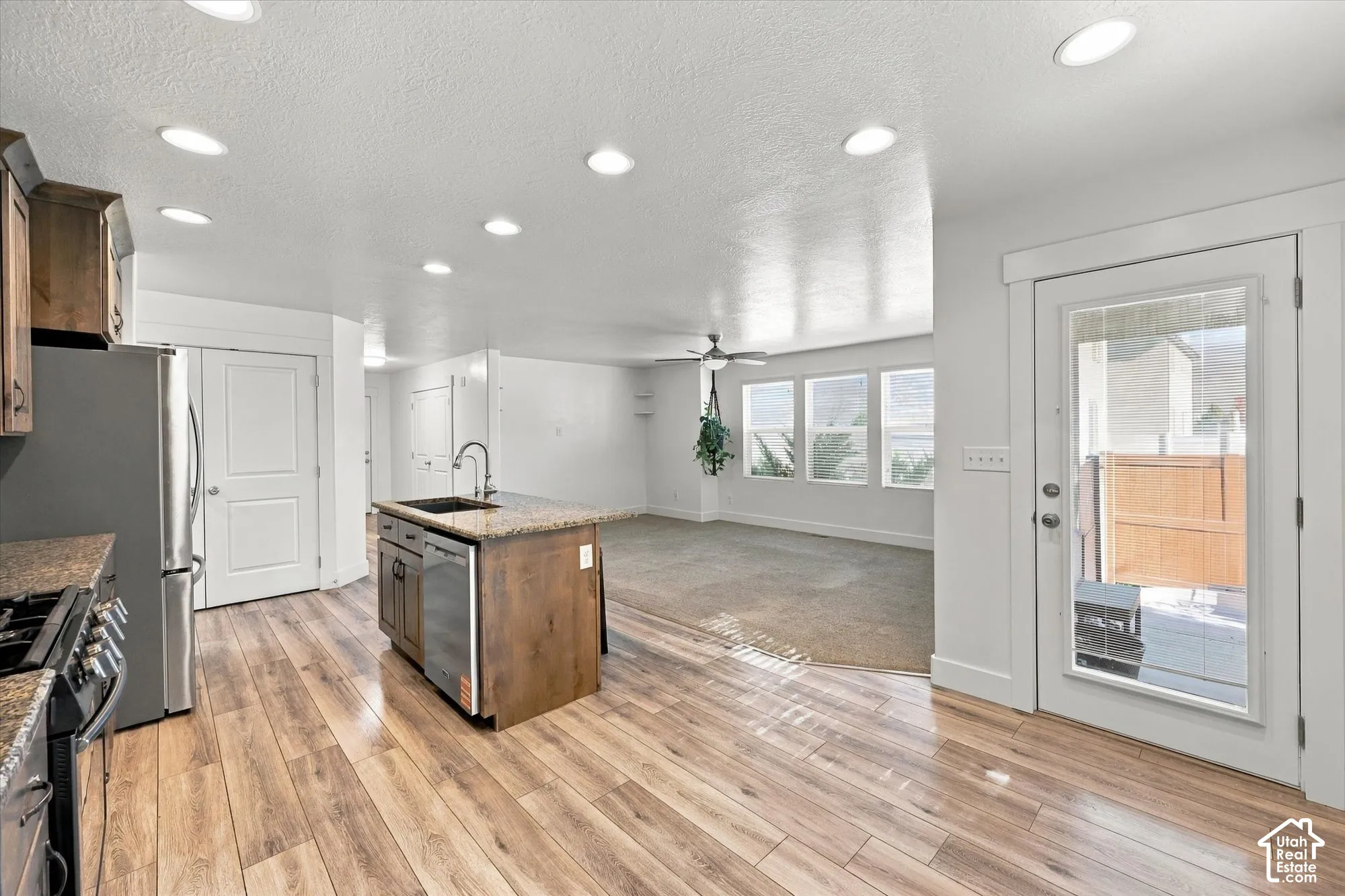 Kitchen featuring wood-finish flooring, a center island with stone-surface countertop, recessed lighting, and a glass-panel exterior door