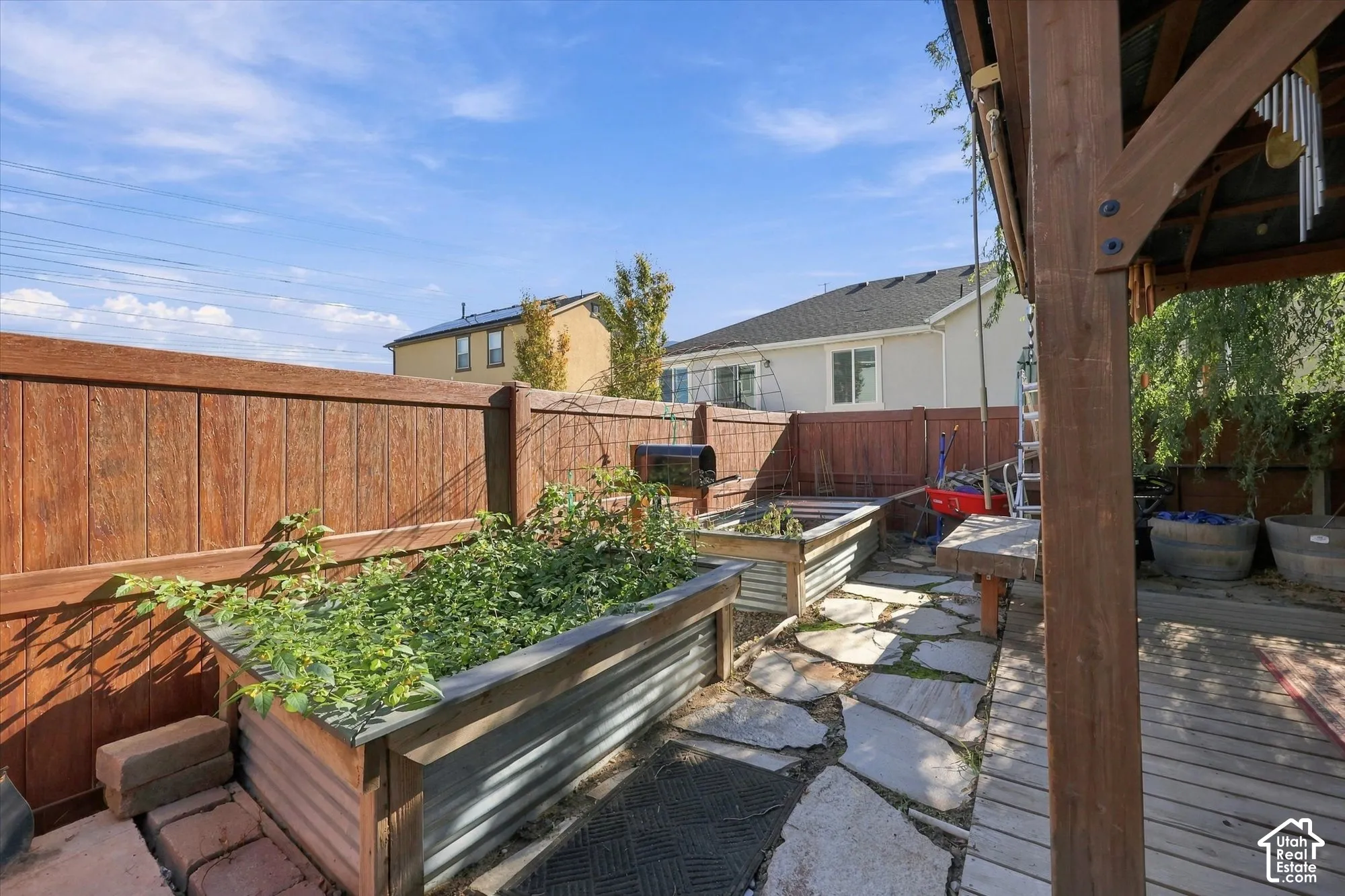 Rear yard featuring a wood privacy fence, raised corrugated metal garden beds, and natural stone flagstone paving