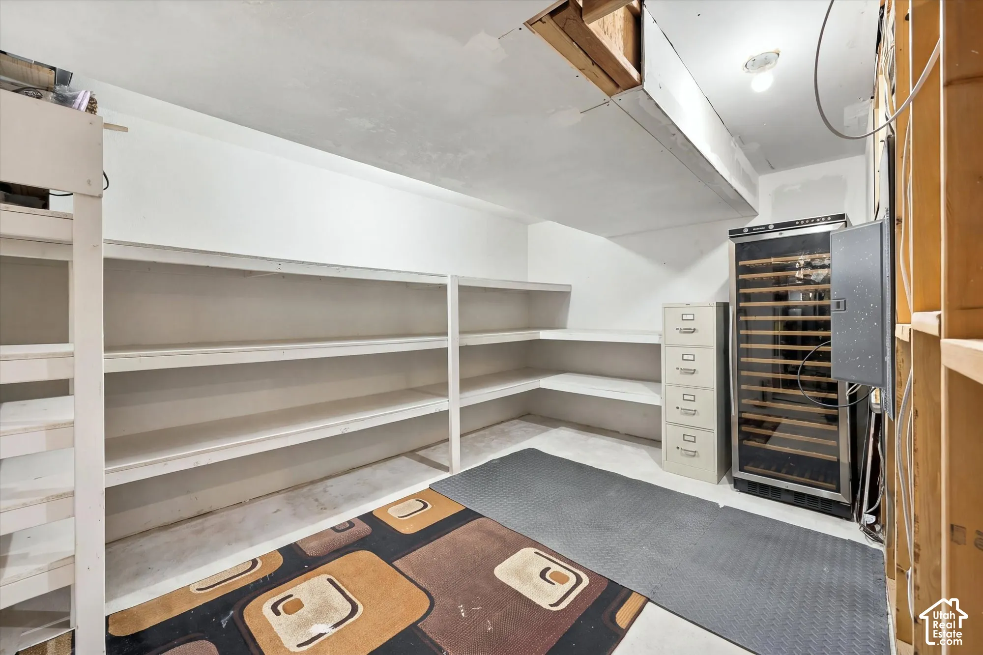 Storage area featuring tiered white built-in shelving and an integrated temperature-controlled wine refrigerator