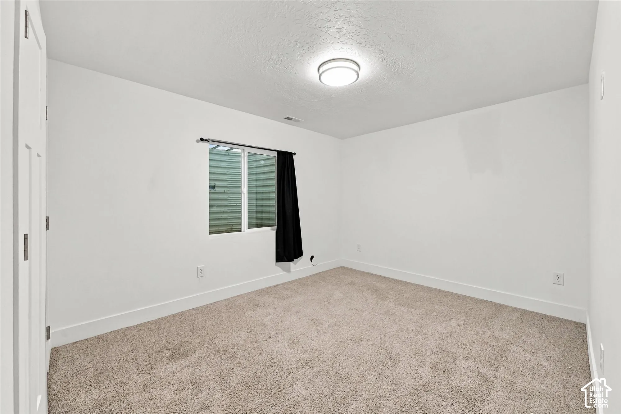 Neutral-toned carpeted flooring, white wall finishes, flush-mount ceiling light fixture, and horizontal slider window
