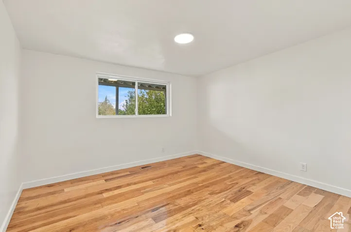 Neutral interior space featuring wood-finish flooring, recessed ceiling lighting, and a dual-pane sliding window