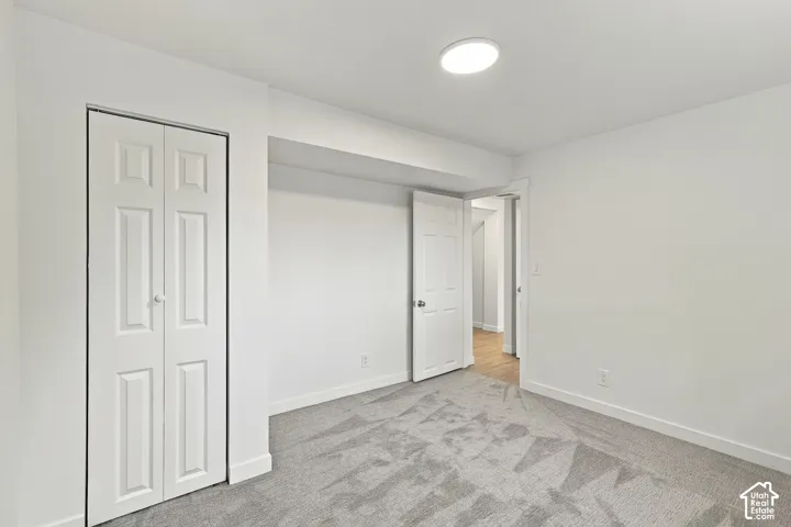 Interior room featuring neutral-toned carpeting, white bi-fold closet doors, a recessed ceiling alcove, and a flush-mount circular light fixture