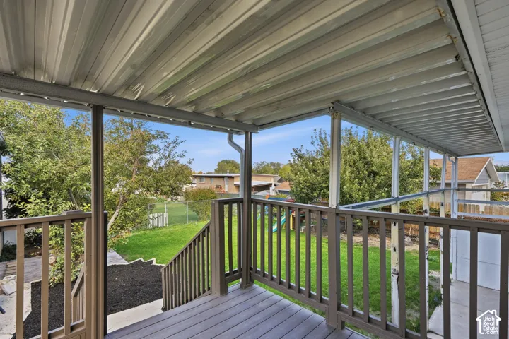 Covered exterior deck with a corrugated metal roof, wood-finish railing, and staircase