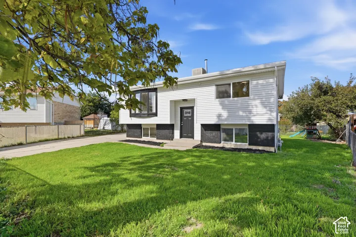 Exterior facade featuring dual-tone siding, contrasting lower masonry, a bay window, and an expansive lawn