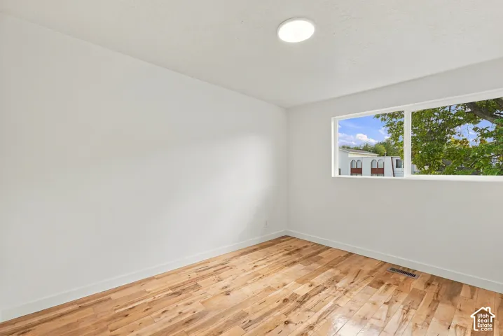 Room featuring wood-finish flooring, white walls, a single-pane horizontal window, and a flush-mount ceiling light fixture