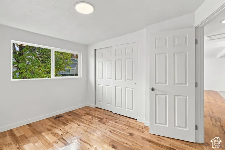 Interior room featuring wood-finish flooring, a double-panel sliding closet, a white paneled door, and a horizontal window