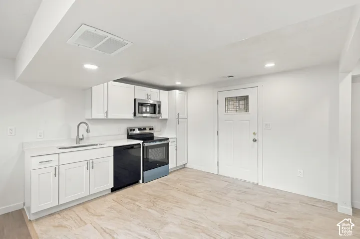 Kitchen featuring white Shaker-style cabinetry, white countertops, stainless steel appliances, recessed lighting, and wood-finish flooring