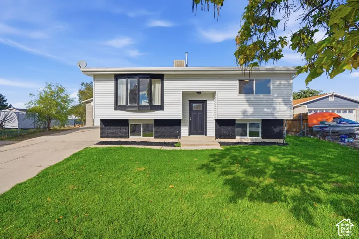 Exterior featuring white horizontal siding, black brick masonry, a prominent bay window, and a concrete driveway