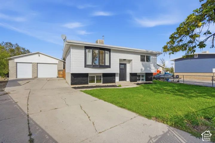 Split-level exterior featuring white horizontal siding, a detached two-car garage, and a front bay window