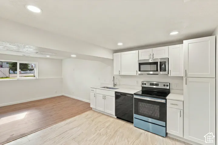Kitchen featuring white shaker-style cabinetry, stainless steel appliances, wood-finish flooring, and recessed ceiling lighting