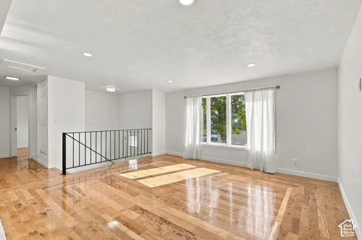 Interior space featuring wood-finish flooring, recessed lighting, and a black metal railing