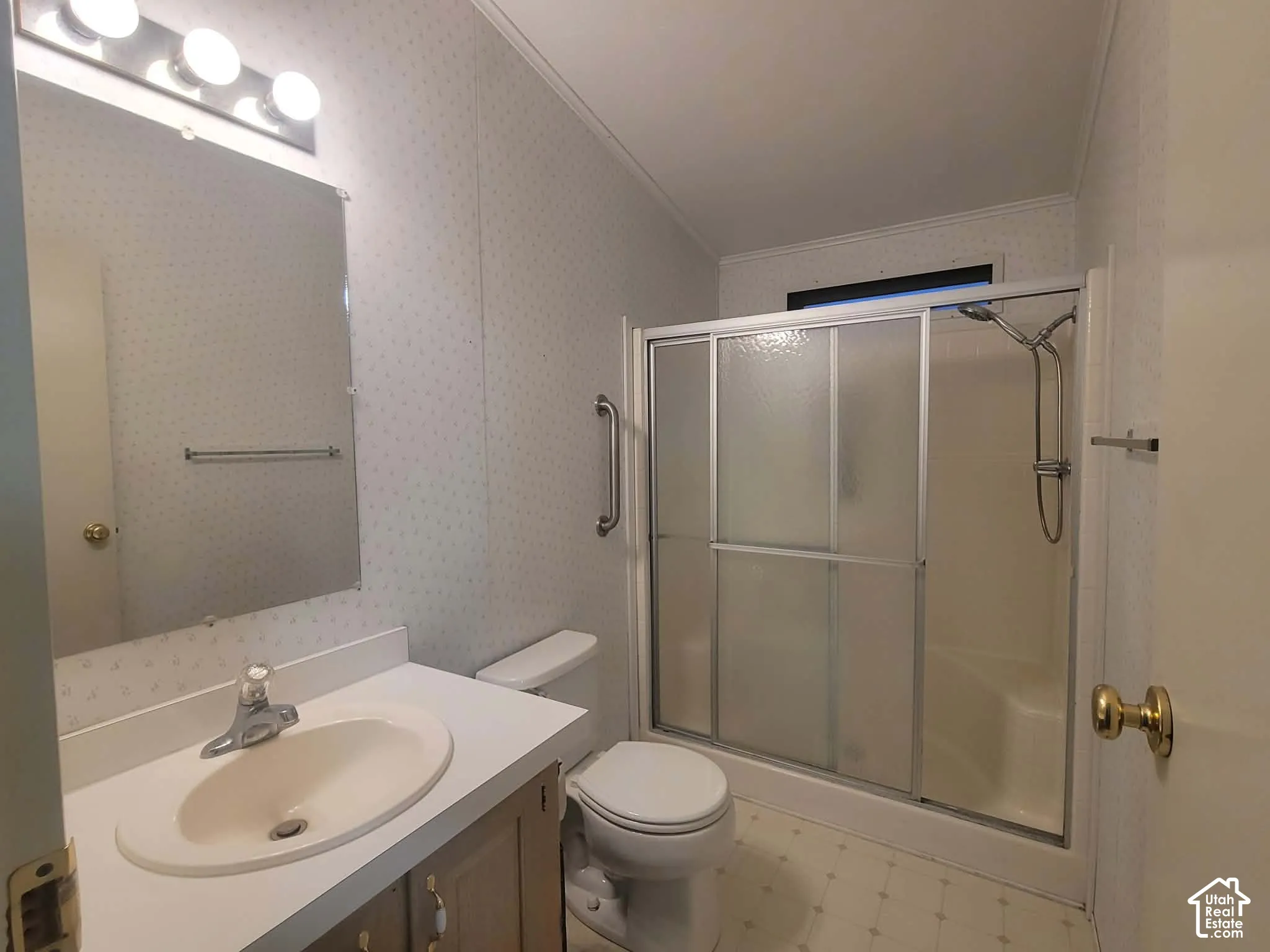 On-suite Bathroom featuring a vanity with an integrated sink, tri-light fixture, shower enclosure with sliding glass doors, and a wall-mounted grab bar