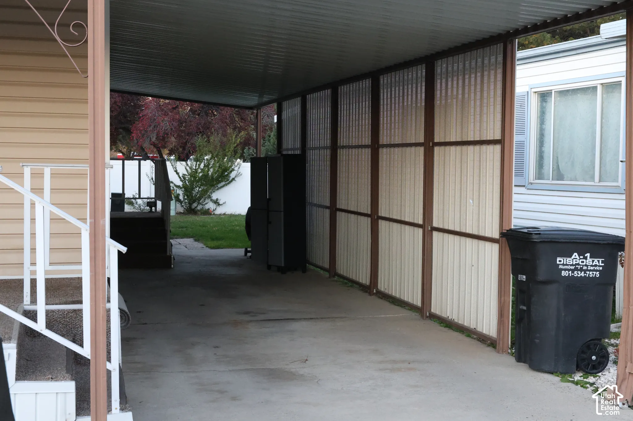 Covered carport featuring a concrete floor, metal structural frame, and privacy screening