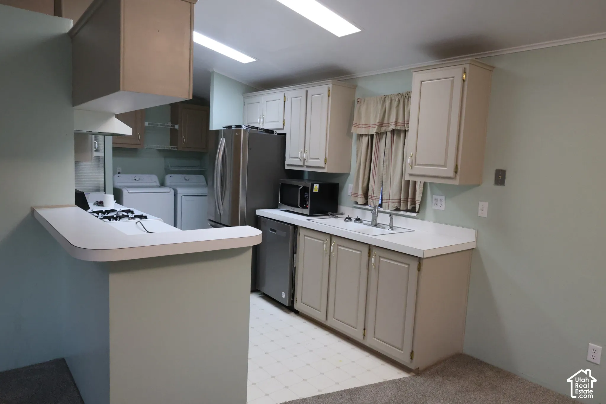 Kitchen featuring cabinetry with neutral-finish doors, solid-surface countertops, integrated stainless steel appliances, and a breakfast bar