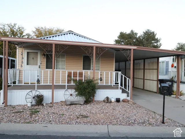 Exterior featuring vinyl siding, a covered front porch with decorative iron detailing, a metal roof, and an attached carport