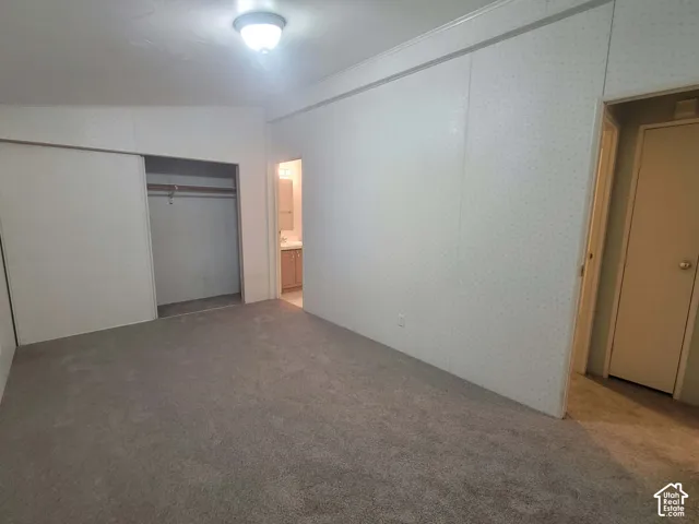 Large Primary Bedroom featuring wall-to-wall carpeting, textured wall panels, a ceiling-mounted light fixture, and a sliding door closet, with on-suite bathroom