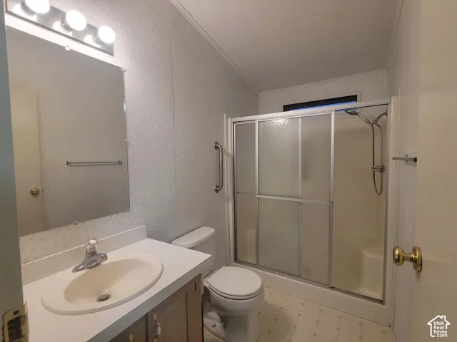 On-suite Bathroom featuring a vanity with an integrated sink, tri-light fixture, shower enclosure with sliding glass doors, and a wall-mounted grab bar