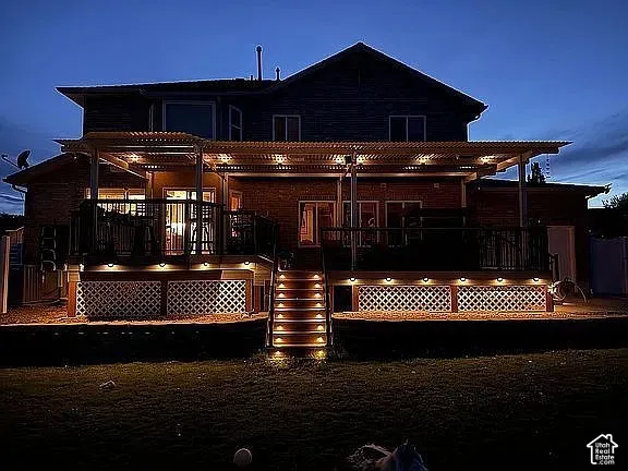 Rear exterior featuring a multi-level deck, structured overhead canopy, lattice privacy skirting, and integrated stair and deck lighting