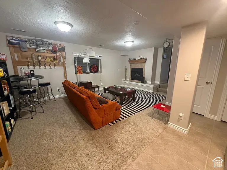 Finished interior space featuring a fireplace with stone-style surround, built-in wooden wall paneling, ceiling-mounted light fixtures, and tiled flooring
