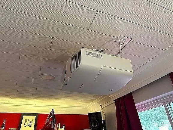 Ceiling-mounted projector with recessed lighting and plank-style ceiling finish
