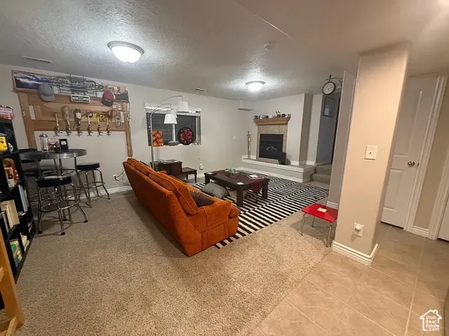 Finished interior space featuring a fireplace with stone-style surround, built-in wooden wall paneling, ceiling-mounted light fixtures, and tiled flooring