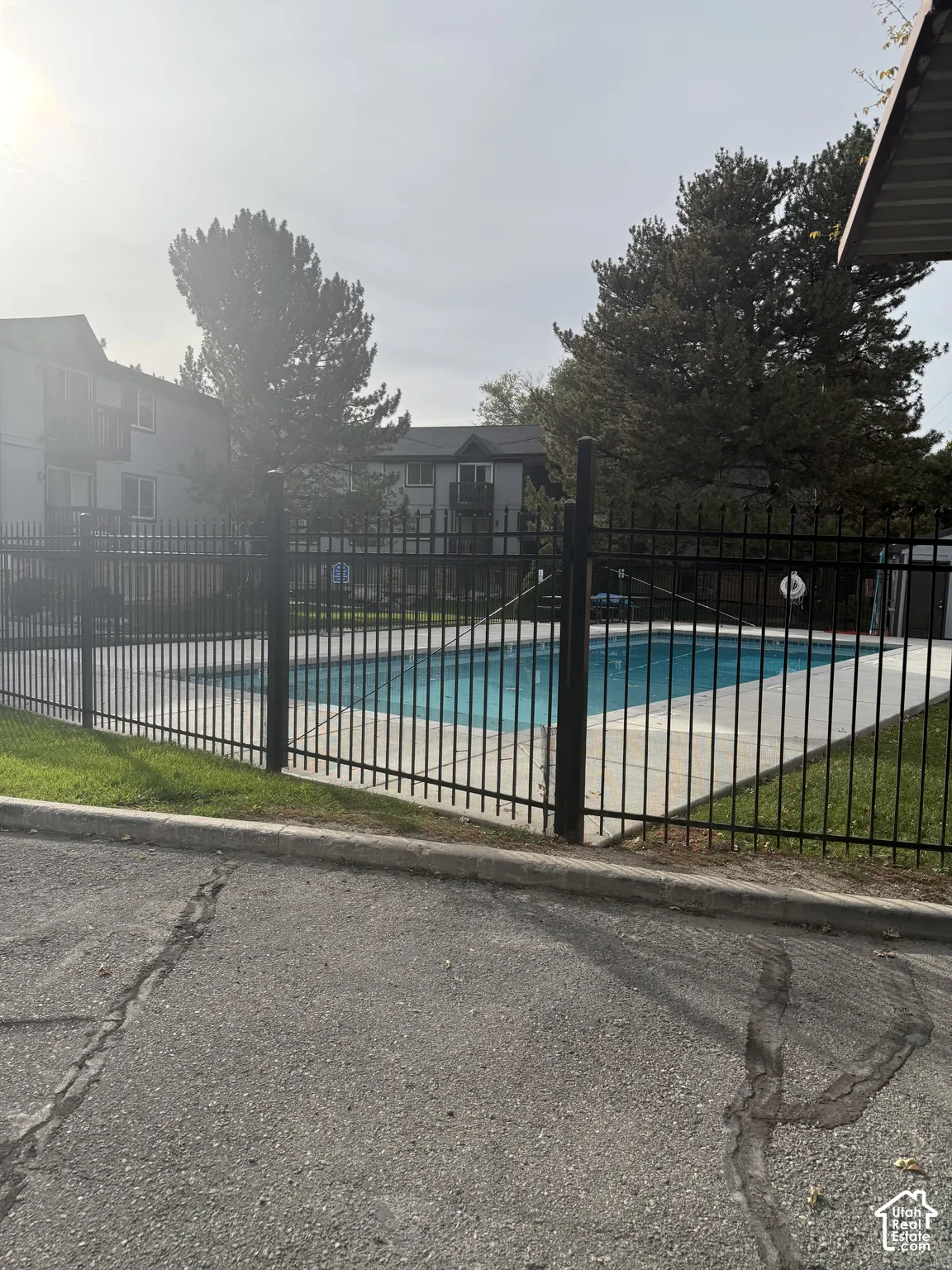 Outdoor swimming pool featuring a concrete deck and a black metal perimeter fence