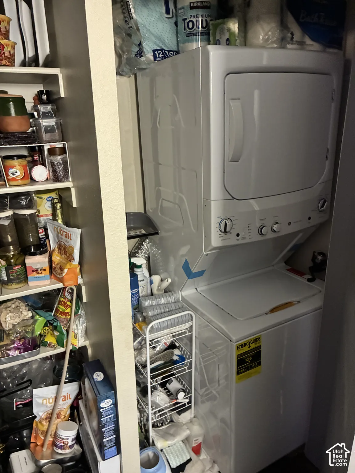Built-in laundry closet featuring a white stacked washer and dryer unit and integrated shelving