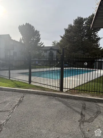 Outdoor swimming pool featuring a concrete deck and a black metal perimeter fence
