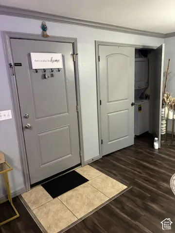 Interior entry featuring wood-finish flooring, a ceramic tile landing, and two-panel interior doors with coordinating gray casing and crown molding