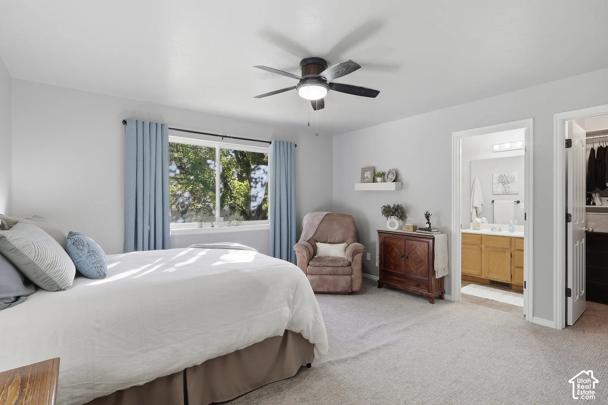Neutral-toned carpeting, ceiling-mounted light fixture with fan, wall-mounted floating shelf, and neutral wall color palette