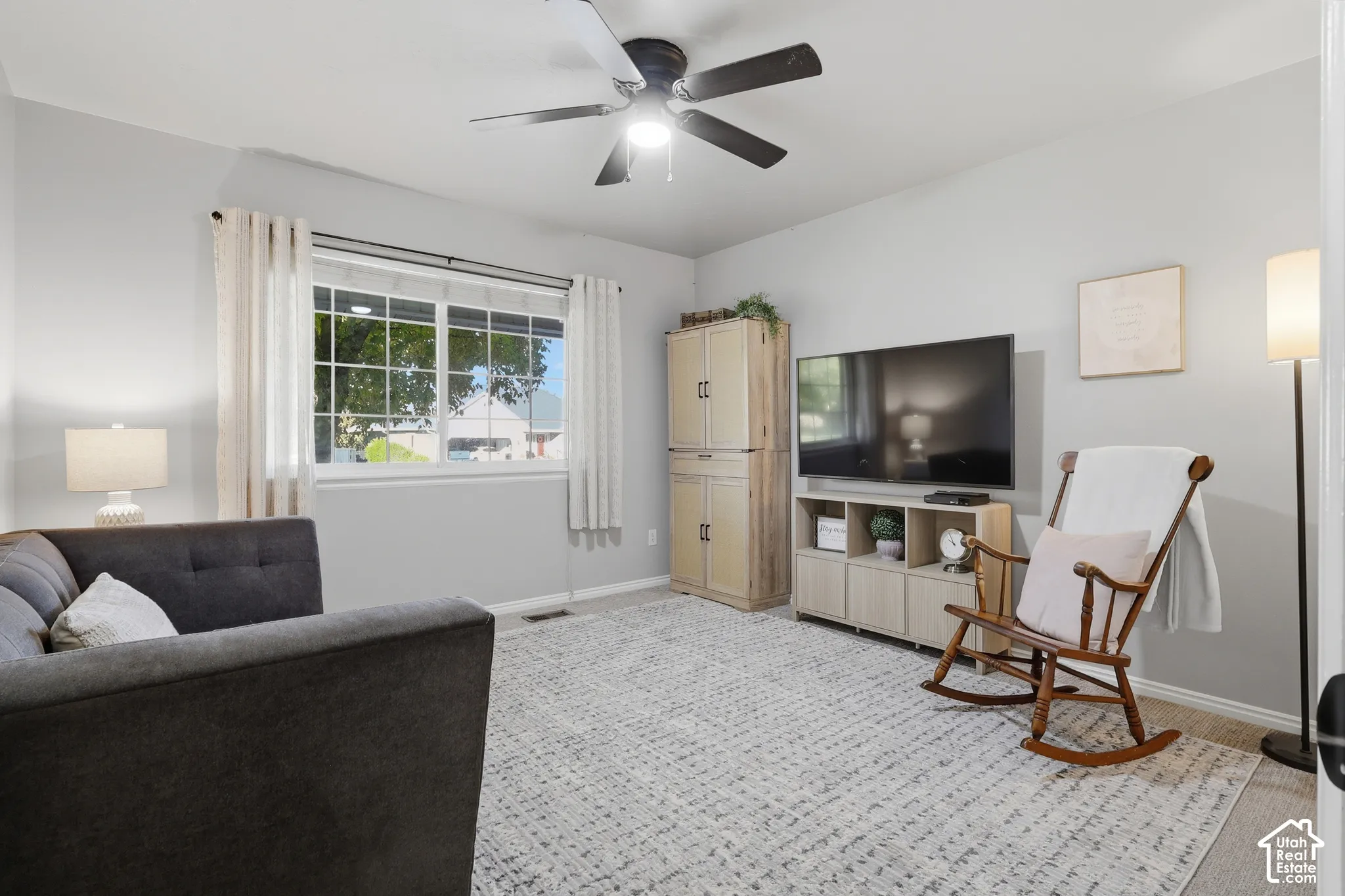 Neutral-toned room featuring a multi-light ceiling fan and a wide-pane window
