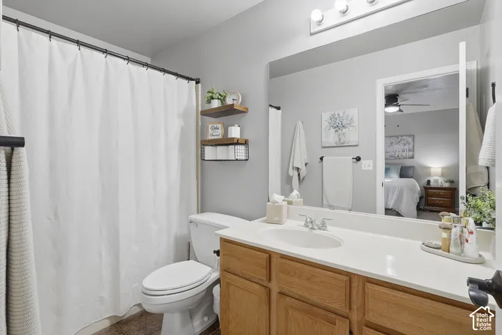 Bathroom featuring a vanity with light wood cabinetry, a solid surface countertop with an integrated basin, a full-width mirror, and a combination tub and shower