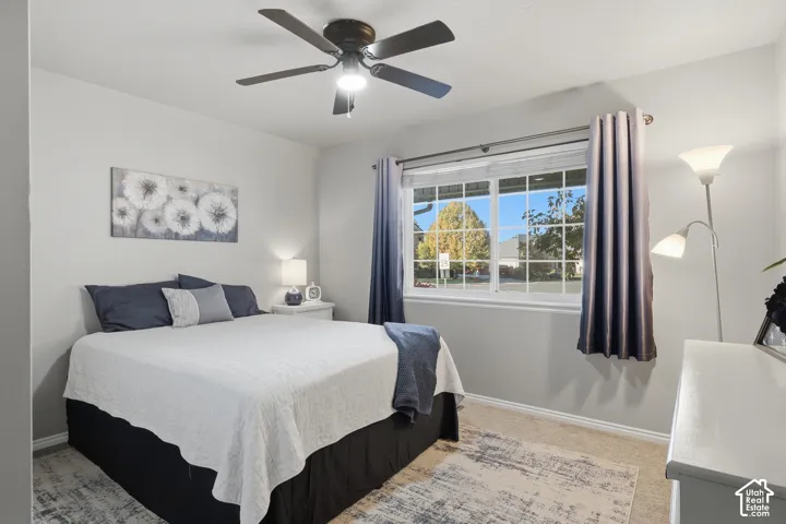 Room featuring neutral wall paint, carpeting, a ceiling fan with integrated lighting, and a large grid-pattern window