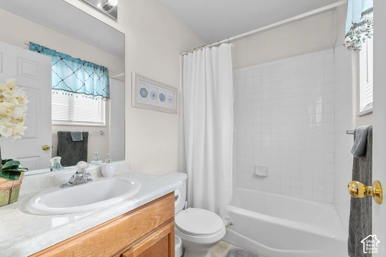 Bathroom featuring a vanity with a light-toned countertop, integrated oval sink, full-width mirror, and a tub-shower combination with white tile surround