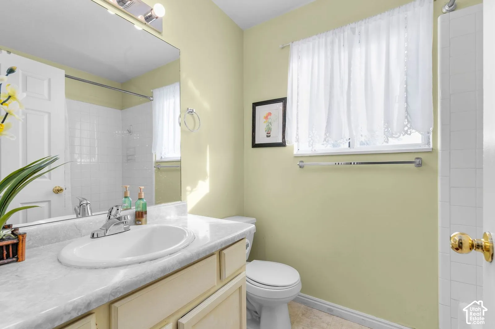 Bathroom featuring a vanity with a light-toned countertop, integrated basin, polished chrome faucet, expansive wall-mounted mirror, and tile-surround shower