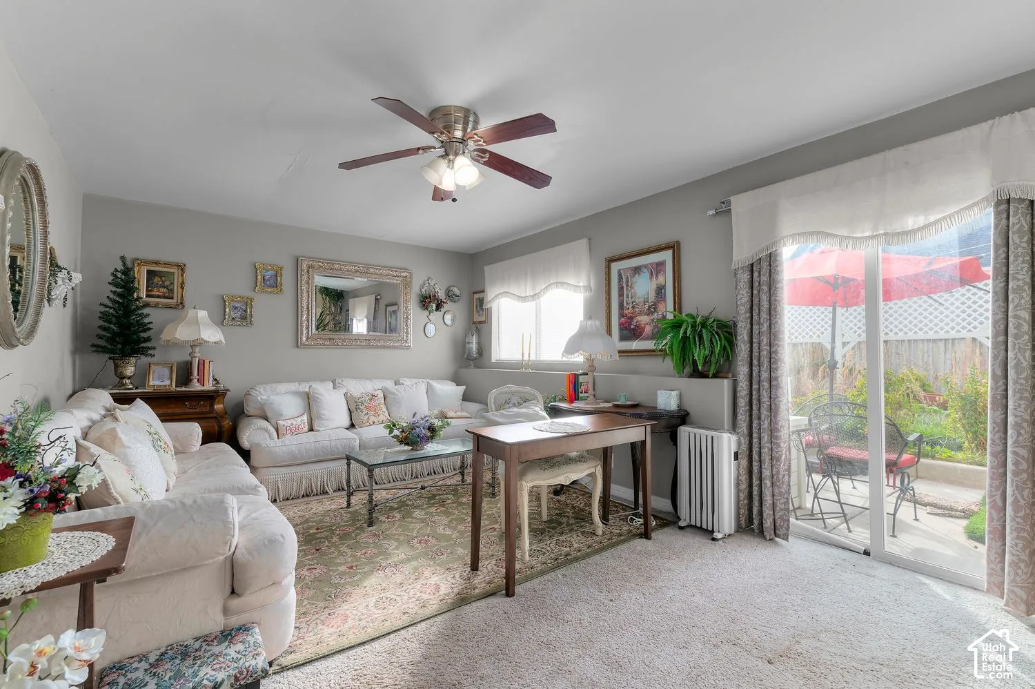 Living space featuring a ceiling fan with integrated lighting, wall-to-wall carpeting, and sliding glass doors with access to an exterior patio