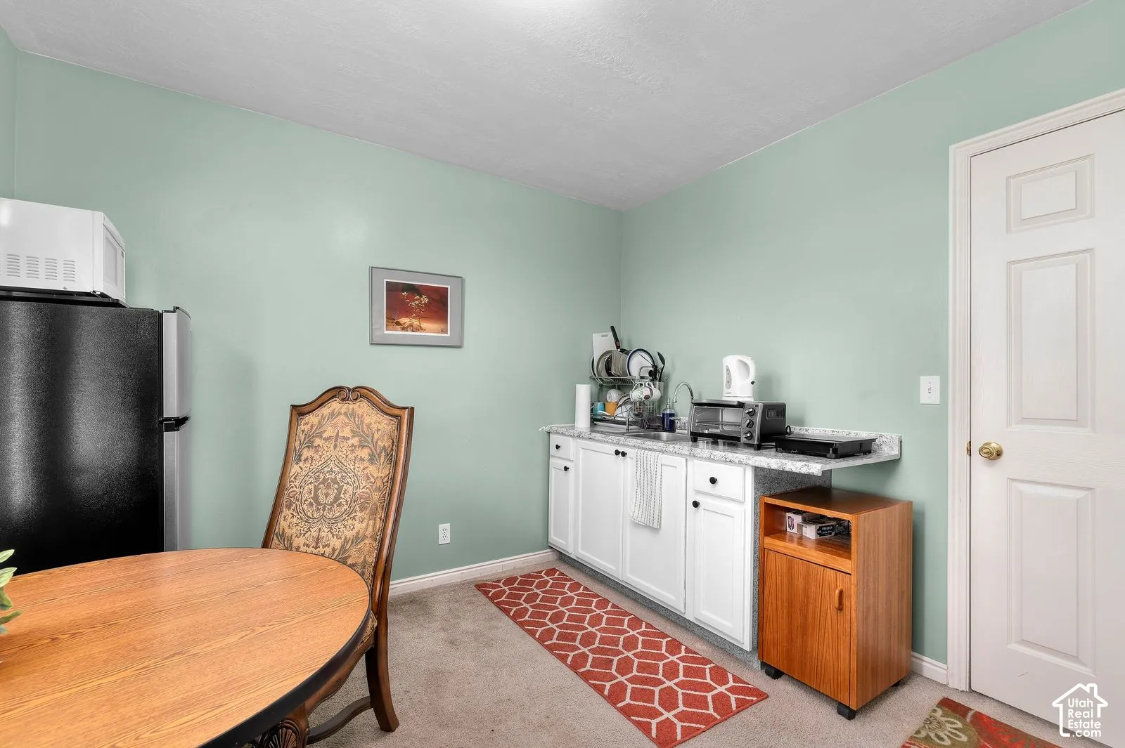 Kitchenette featuring white cabinetry, stone-finish countertops, stainless steel sink, and a six-panel interior door