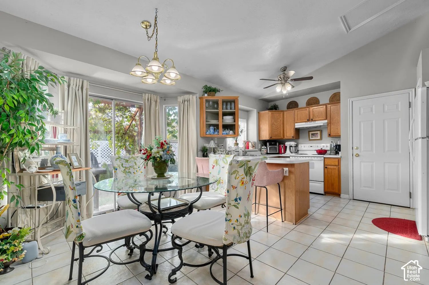 Kitchen featuring wood cabinetry, a center island with a breakfast bar, ceramic tile flooring, a vaulted ceiling, and glass sliding doors