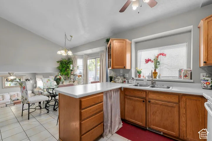 Kitchen featuring solid wood cabinetry, a peninsula with a composite countertop, a stainless steel double-basin sink, and tile flooring
