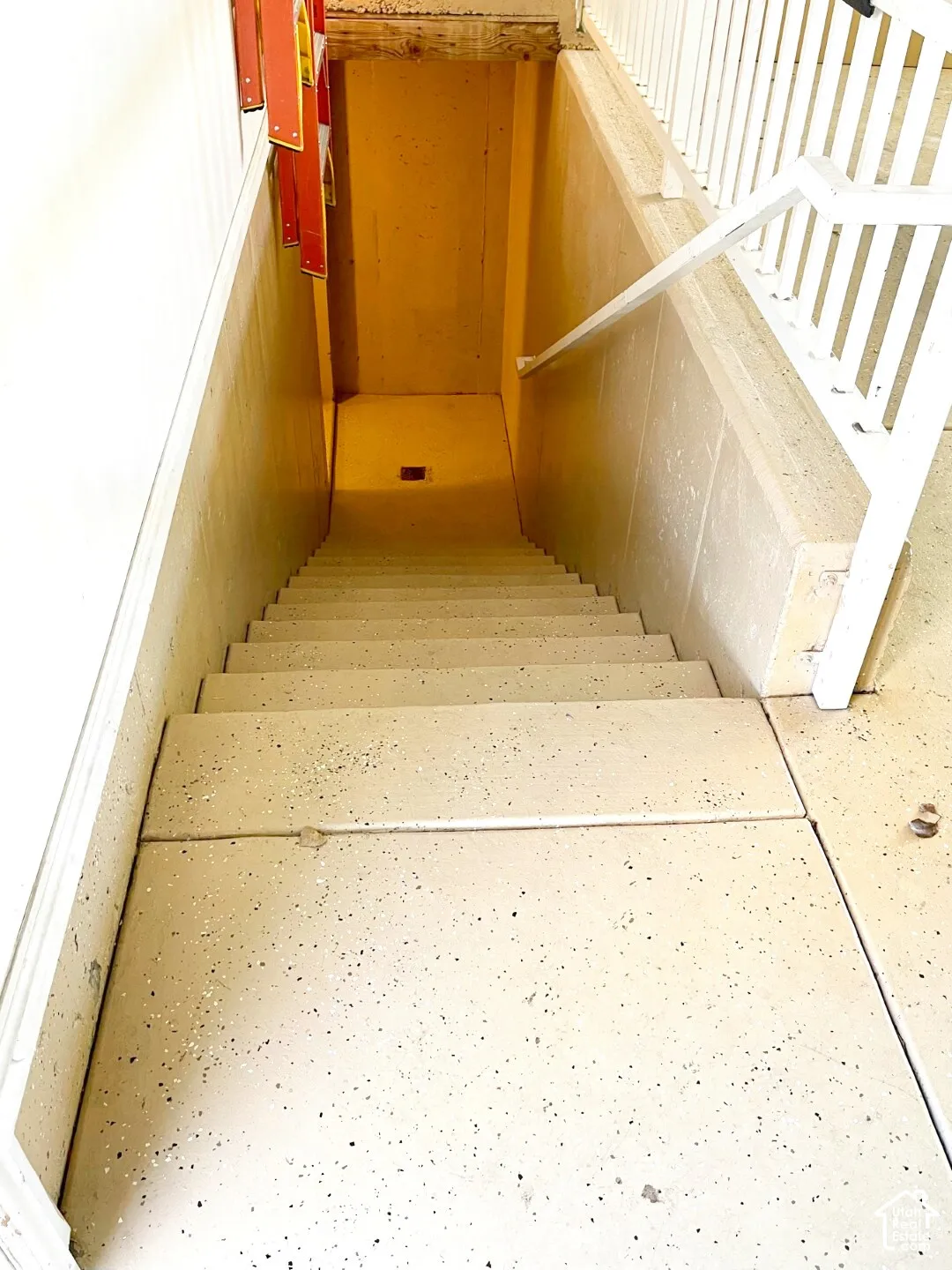 Staircase featuring a speckled epoxy-finish surface, white metal railing, and concrete-block walls