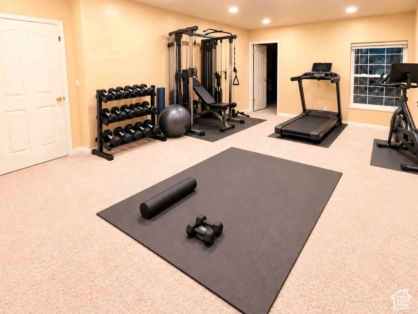 Spacious room featuring neutral carpeting, recessed ceiling lighting, and a multi-pane window