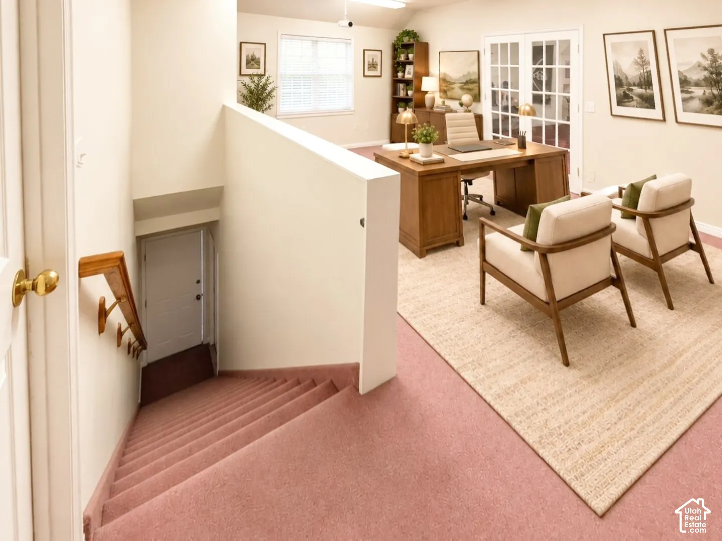 Carpeted staircase featuring a wooden handrail and wall-mounted brackets, multi-pane window, and French doors