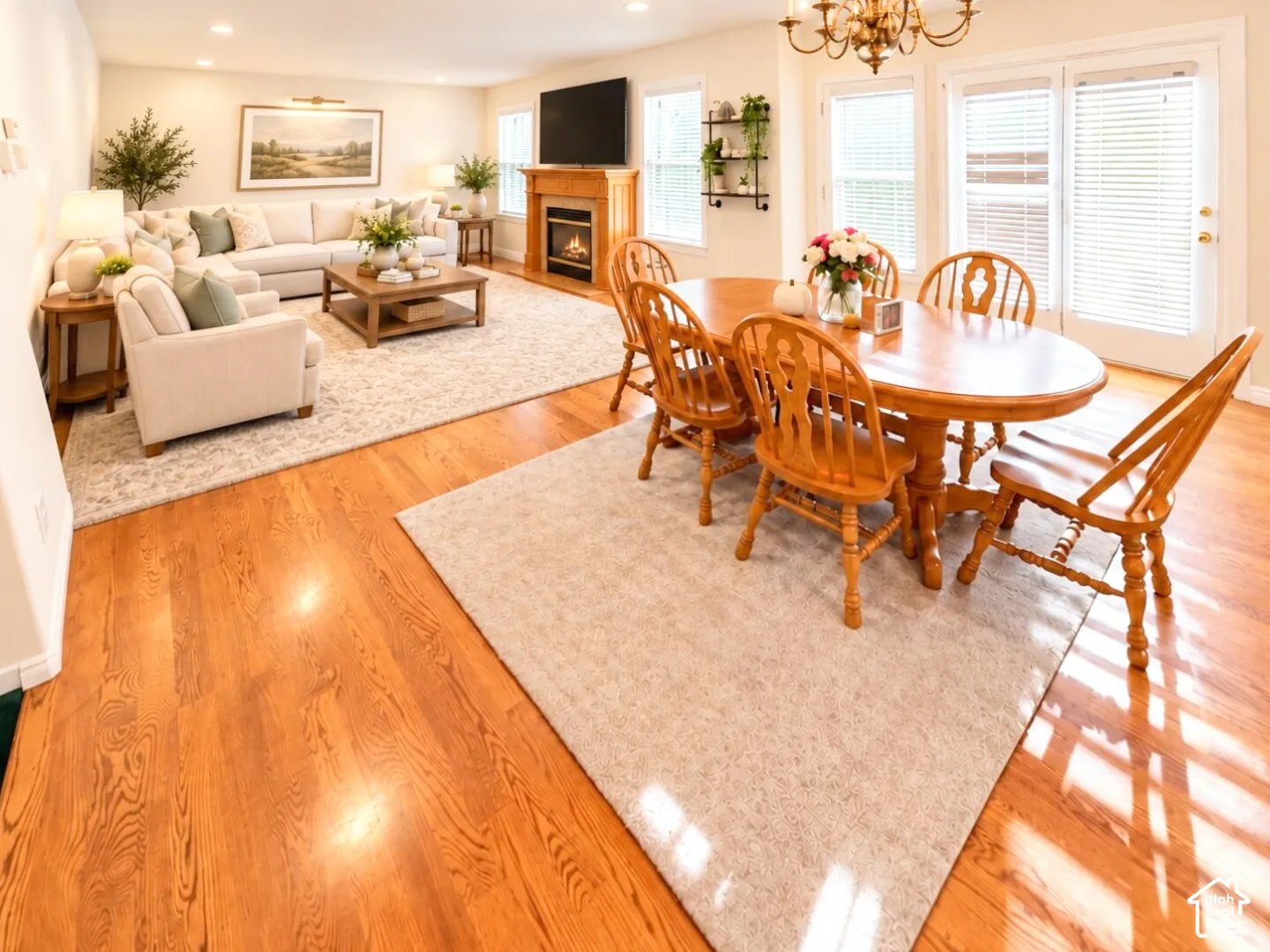 Open-concept living and dining area featuring wood-finish flooring, a fireplace with a wood mantel, recessed lighting, a chandelier, and glass-paned double doors