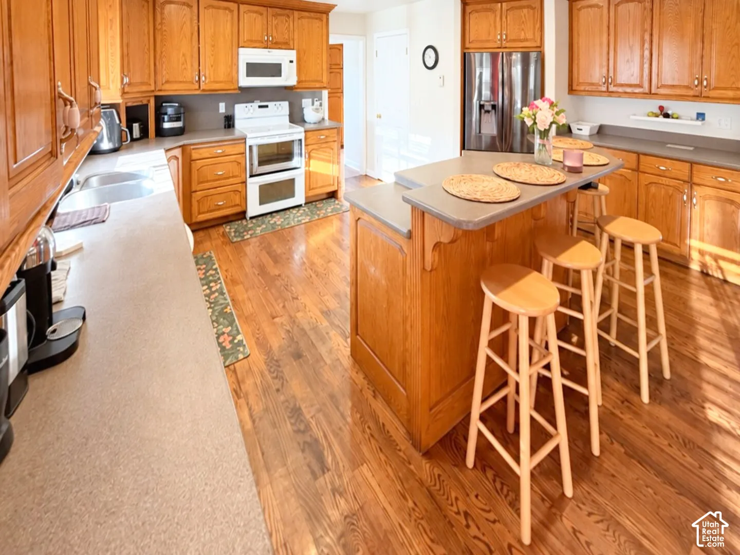 Kitchen featuring wood-finish cabinetry, a tiered center island with bar seating, solid-surface countertops, and wood-finish flooring